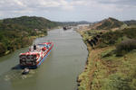 Foto, Bild: Die engste Strecke des Panamakanals, der Corte Gaillard, hinten die Pedro Miguel Schleuse und die Hochhäuser von Panama City